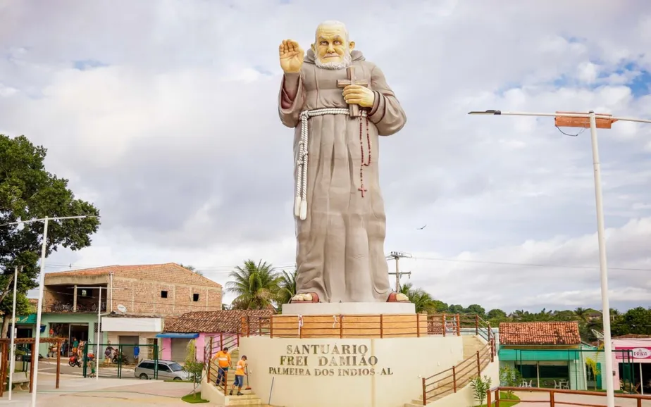 estátua com frei damião segurando uma bíblia e com a mão levantada